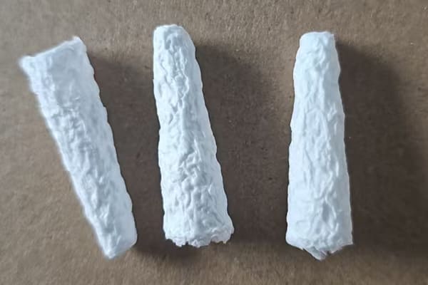 A charred and broken cellulose thimble next to an intact one to show heat damage